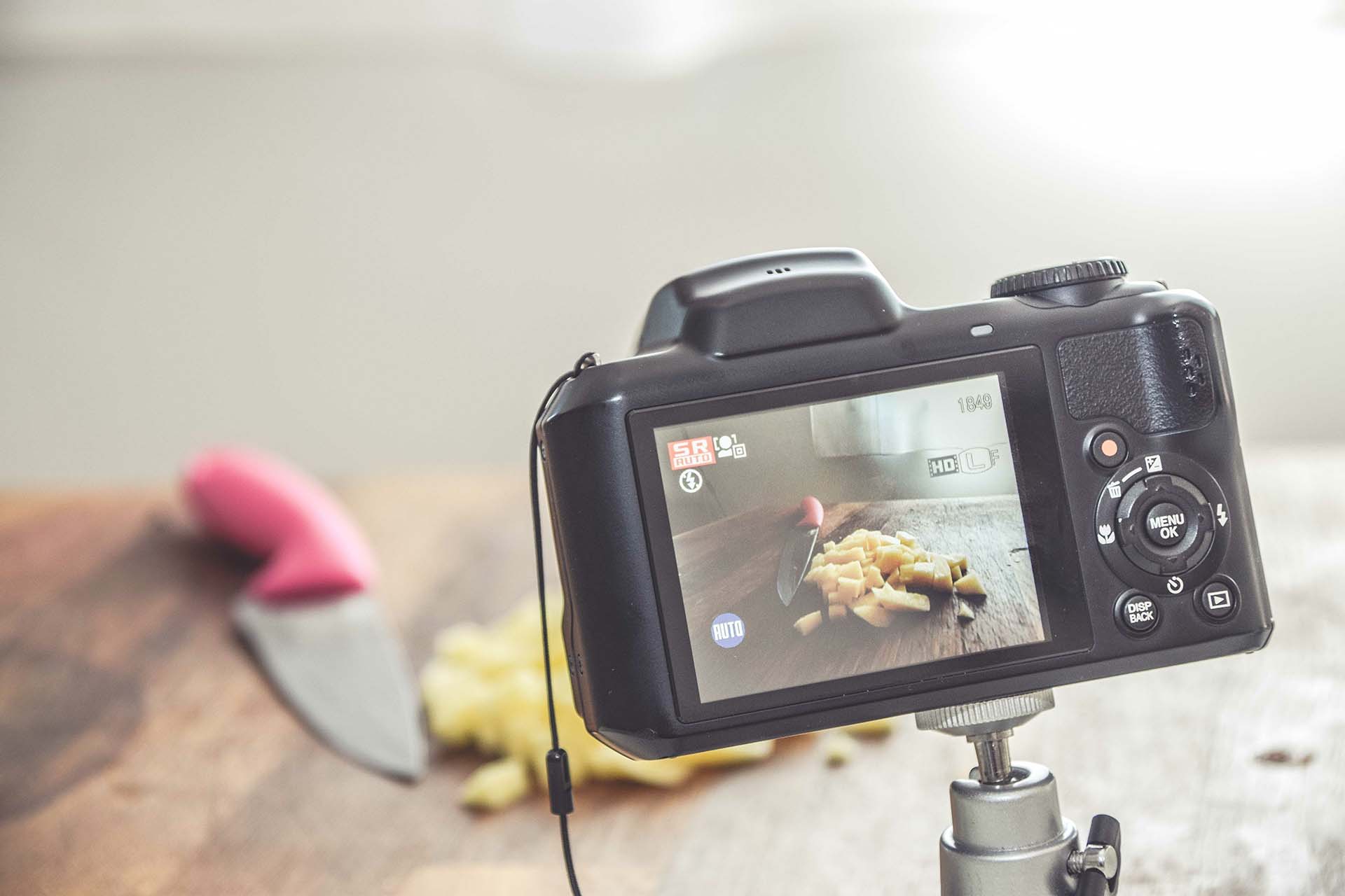 Product Photography Tips: a picture of a kitchen knife in use, artfully laid next to chopped veg and viewed through the viewing pane of a camera