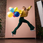 Product Photography Tips: a lady leaping with balloons for a photoshoot, neutral background