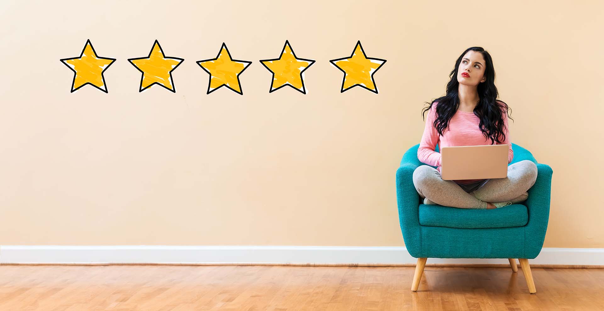 The Importance of Customer Reviews and How to Encourage Them - woman sat in a chair looking thoughtful with a laptop and five stars to her left