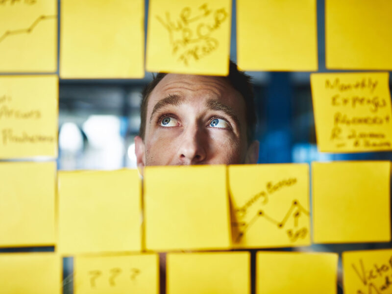 Sitemaps - The Secret Roadmap Your Website Can’t Do Without - this image shows a clear screen with yellow sticky notes blocking the view except for a letterbox shaped holke where you can see a mans face viewing the detail with a confused look on his face